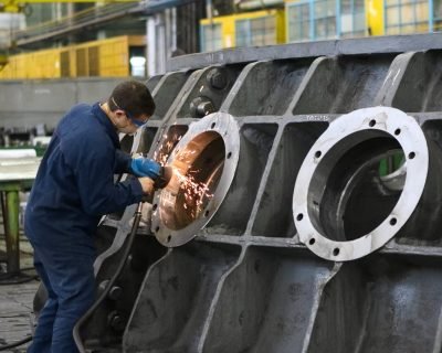 A worker in protective gear grinding metal, creating sparks in a factory setting.