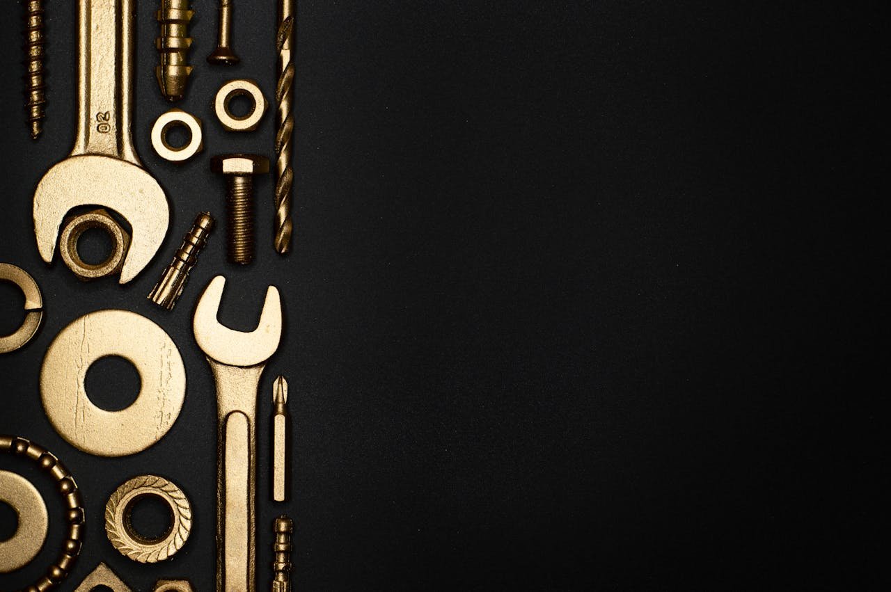 Gold-colored tools arranged on a black background with ample copy space, ideal for industrial themes.